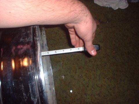 1993 Ford Bronco - A tape measure is used to check the width of a chrome bumper, indicating its dimensions.