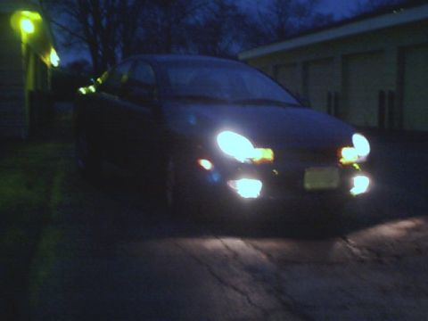 2000 Dodge Neon - A dark sedan is parked outside at night with its headlights illuminated.