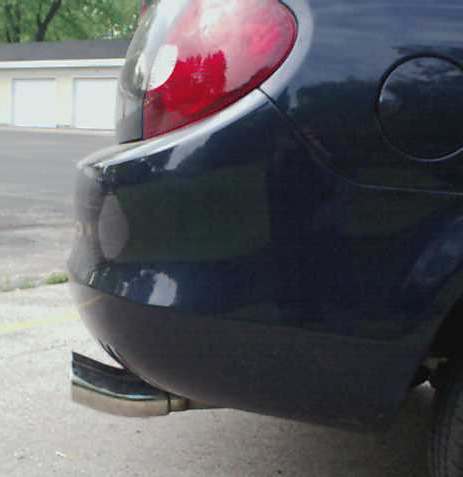 2000 Dodge Neon - The rear quarter panel and taillight of a dark-colored hatchback are visible, with a visible exhaust pipe.