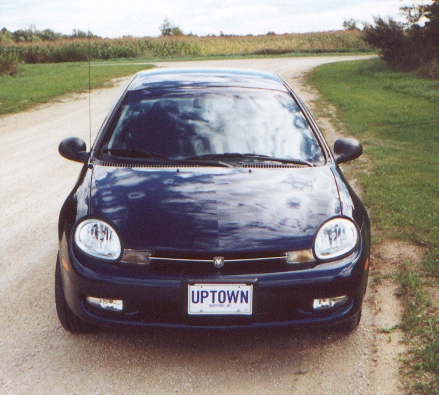 2000 Dodge Neon - A dark blue 2000 Dodge Neon is parked on a dirt road with a cornfield in the background.