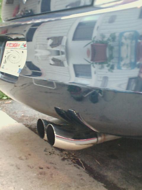 2000 Dodge Neon - Dual exhaust pipes are visible on the rear of a car, with reflections on the bumper.