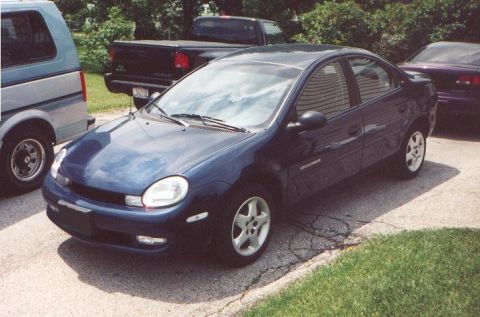 2000 Dodge Neon - A dark blue Dodge Neon sedan is parked on asphalt, with other vehicles visible in the background.