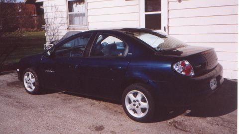 2000 Dodge Neon - This dark blue 2000 Dodge Neon sedan is parked in a driveway next to a house.