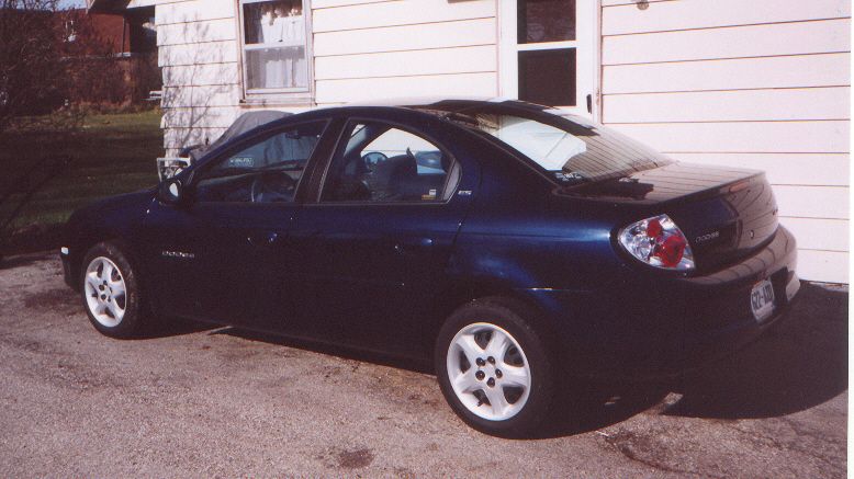 Dark blue 2000 Dodge Neon sedan parked outside a white house