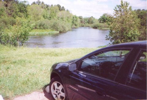 2000 Dodge Neon - A Dodge sedan is parked near a body of water with trees in the background.