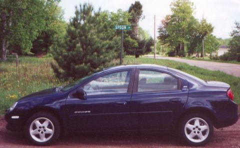 2000 Dodge Neon - Side view of a dark blue 2000 Dodge Neon sedan parked on a dirt road.