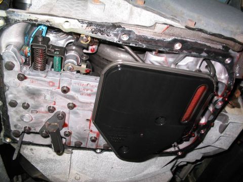 2000 Dodge Neon - Close-up view of a vehicle's transmission pan and filter assembly, with red fluid present.