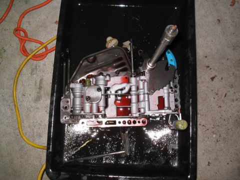2000 Dodge Neon - A disassembled automatic transmission valve body sits in a pan with used fluid.
