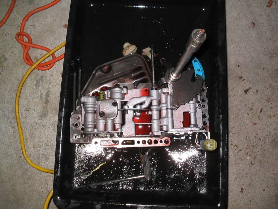 Automatic transmission valve body with red fluid in a black pan