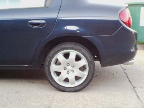 2000 Dodge Neon - Rear side view of a dark blue 2000 Dodge Neon sedan, focusing on the wheel and body panel.