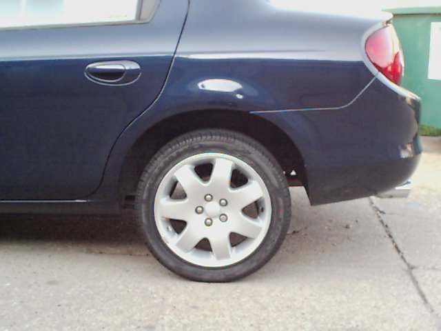 Dark blue 2000 Dodge Neon sedan, rear passenger side view, showing wheel and quarter panel