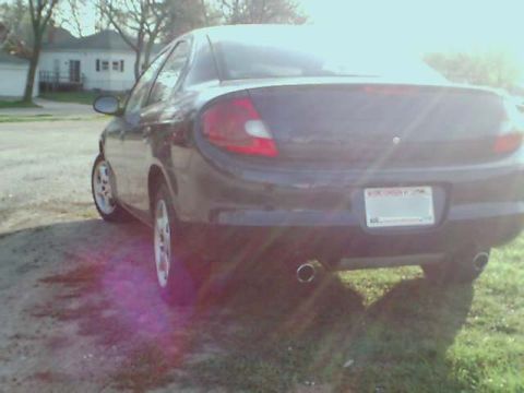 2000 Dodge Neon - The rear of a dark sedan, identified as a 2000 Dodge Neon, is shown from a low angle.