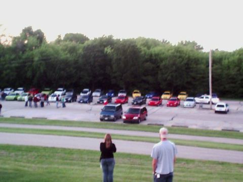 2000 Dodge Neon - A large group of cars are parked in a lot, with people observing them from a distance.