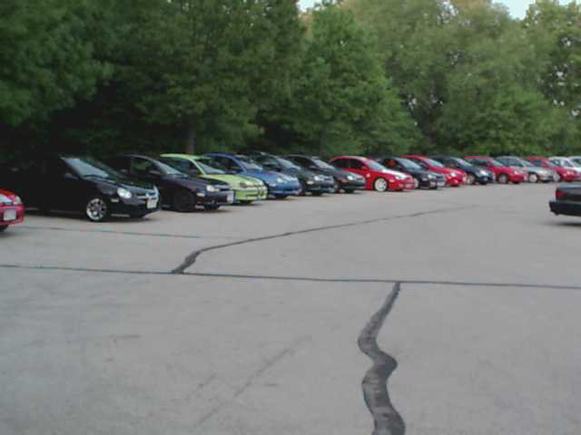 Line of sedans parked in a lot, with trees in the background. A watermark reads SUPERMOTORS