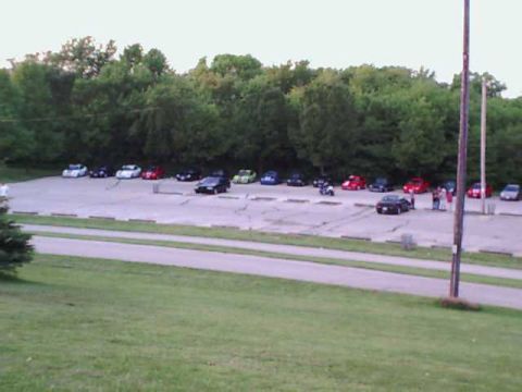 2000 Dodge Neon - A parking lot scene with numerous vehicles gathered under a tree line.