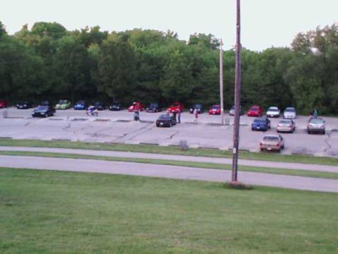 2000 Dodge Neon - A variety of vehicles are parked in an outdoor lot, with a line of trees visible behind them.