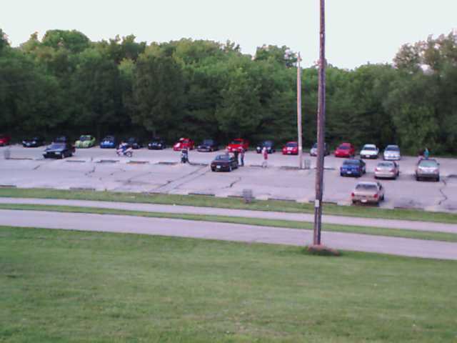 Cars parked in a lot with trees in the background