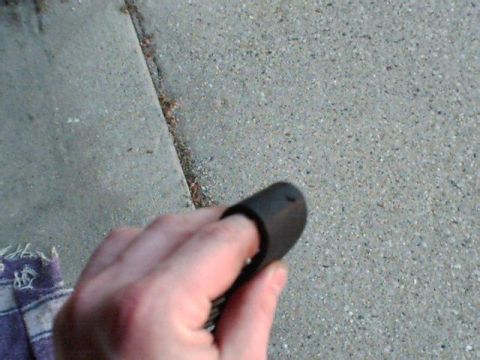 1995 Plymouth Neon - A hand holds a black rubber component against a textured concrete surface.