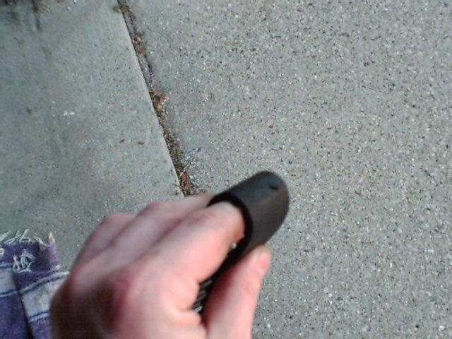hand holding a black rubber part over concrete ground
