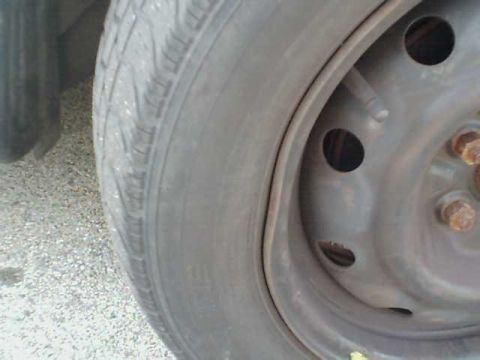 1995 Plymouth Neon - A close-up view of a tire and its steel wheel, showing lug nuts and the tire's tread pattern.