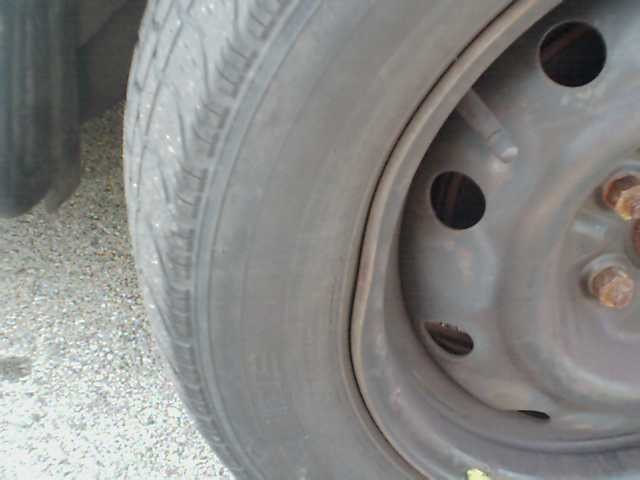 Close-up of a tire and steel wheel with visible lug nuts