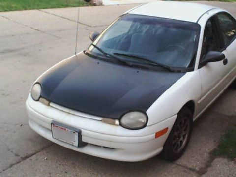 1995 Plymouth Neon - A white Plymouth Neon with a contrasting black hood sits parked on a paved surface.