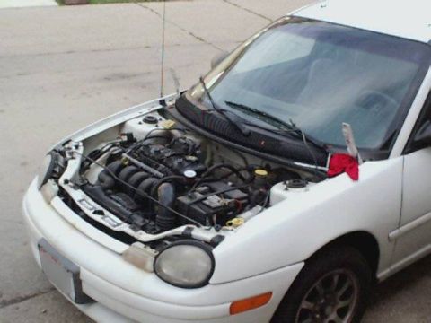 1995 Plymouth Neon - A white 1995 Plymouth Neon sedan is shown from the front with its hood open, revealing the engine compartment.