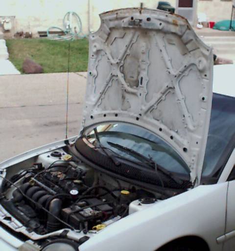 1995 Plymouth Neon - The engine bay of a white car is visible with the hood raised, showing the engine components and a Supermotors.net watermark.