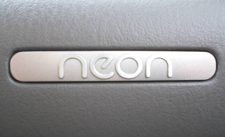 Close-up of a 'neon' emblem on a gray interior panel