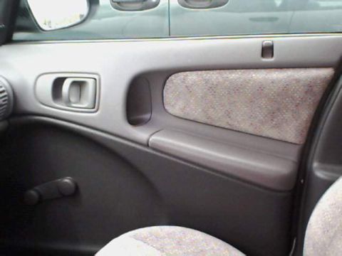 1995 Plymouth Neon - Close-up of a car's interior door panel, showing the fabric insert and manual window crank.