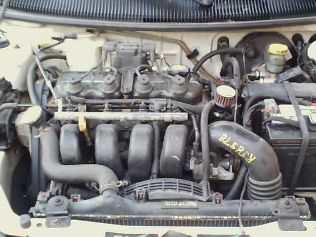 Engine bay with black intake hose marked "BLSRLY", yellow fluid reservoir, and battery