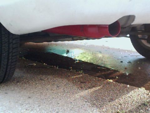 1995 Plymouth Neon - A red exhaust pipe is visible on the underside of a white vehicle.