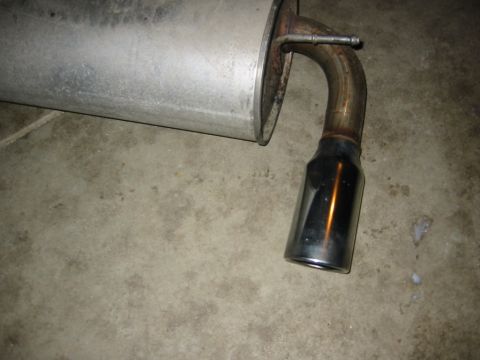 1995 Plymouth Neon - Close-up of a vehicle's exhaust pipe, showing the muffler and chrome tip.