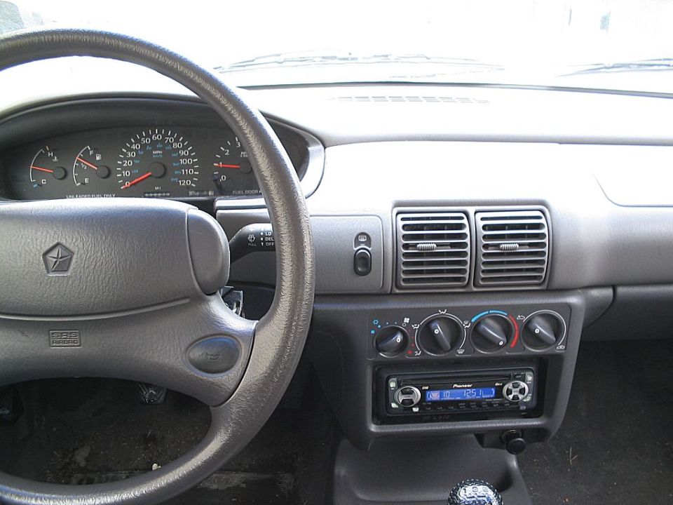 Gray dashboard and steering wheel of a 1995 Plymouth Neon, showing gauges, air vents, and a Pioneer stereo