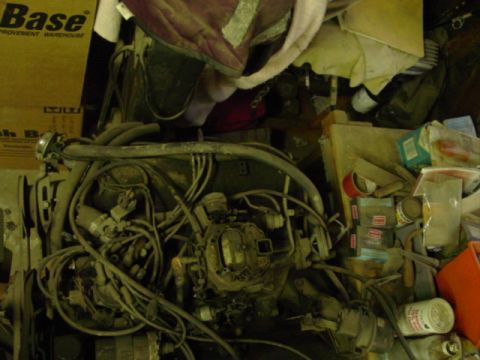 1978 Ford Bronco - Engine parts and assorted items piled together in a cluttered space.