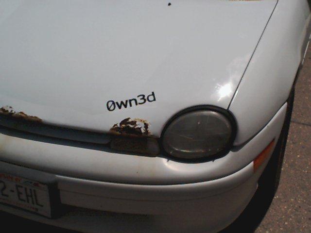 White car hood with rust spots near the front and an 'Own3d' sticker