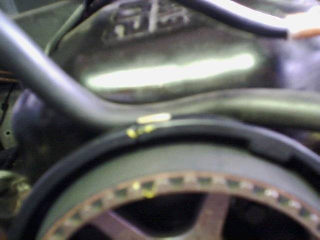 Close-up of a toothed metal pulley with a black rubber belt, part of a vehicle's engine
