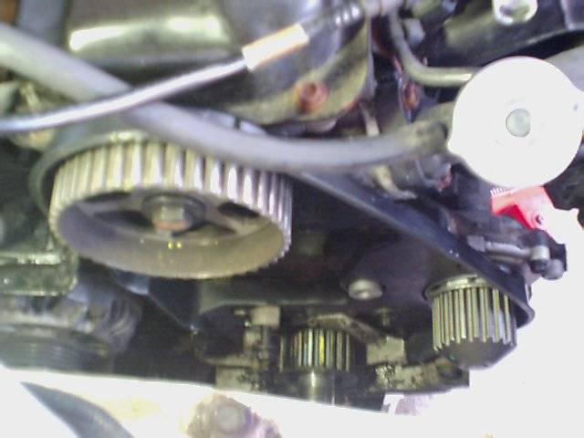 Close-up of engine timing belt and pulleys, with a white cap visible on the right