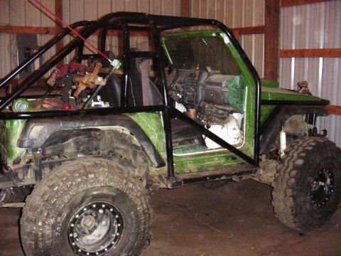 1992 Ford Bronco - This heavily modified off-road vehicle features an extensive roll cage and a green exterior, with its interior partially exposed.