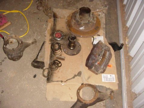 1992 Ford Bronco - Disassembled vehicle brake and suspension components are spread out on a piece of cardboard.