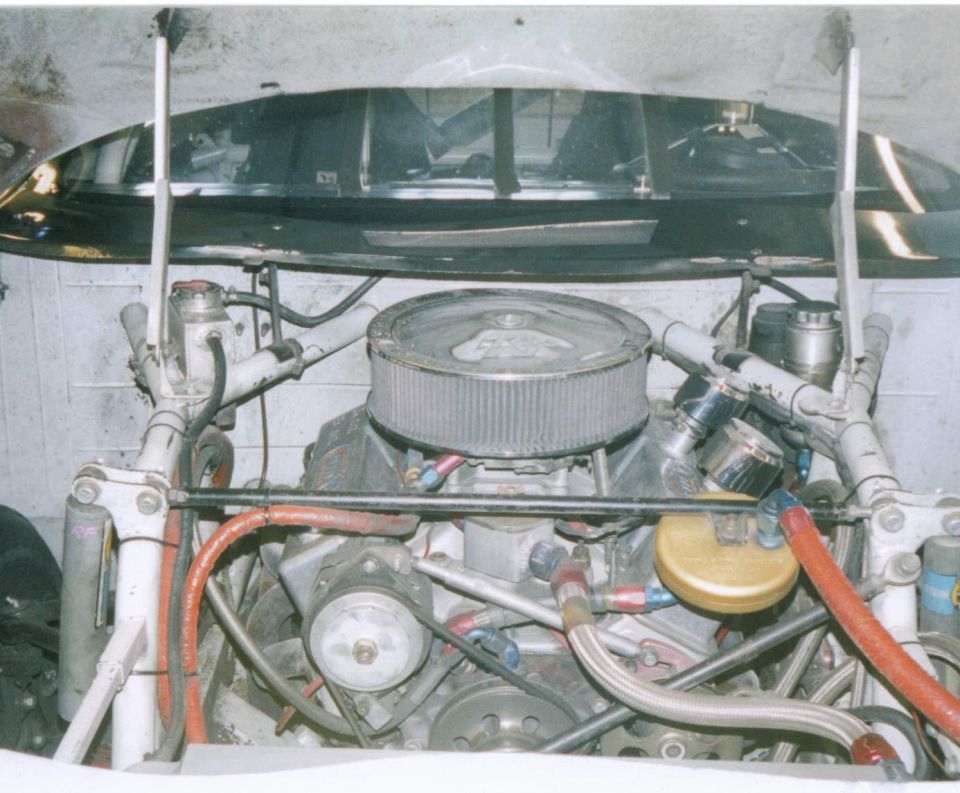 Engine bay of a race car with a large air filter and complex plumbing