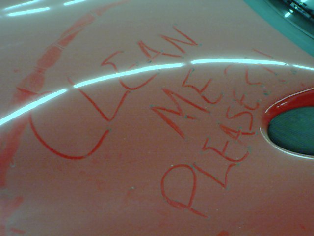 Red car hood with 'CLEAN ME PLEASE' written on it in red marker