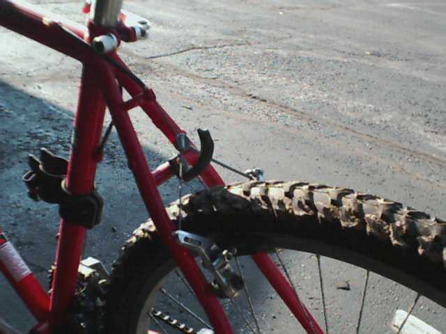 Red bicycle frame and knobby tire with mud on the tread