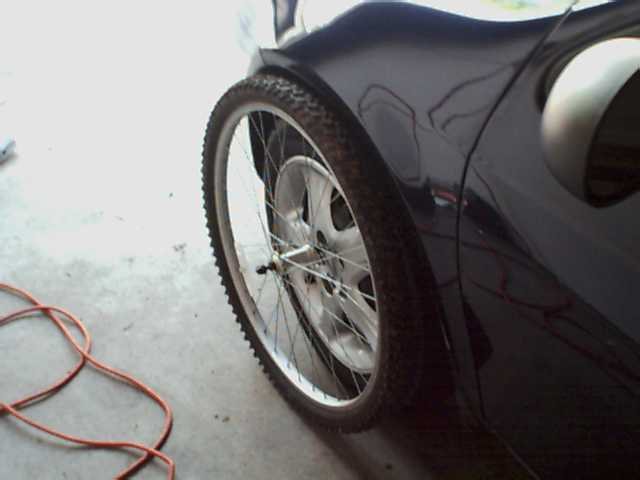 Dark car fender and wheel with knobby tire, side view