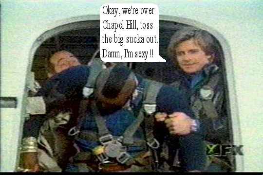 Two men in a cockpit, one is wearing a parachute harness