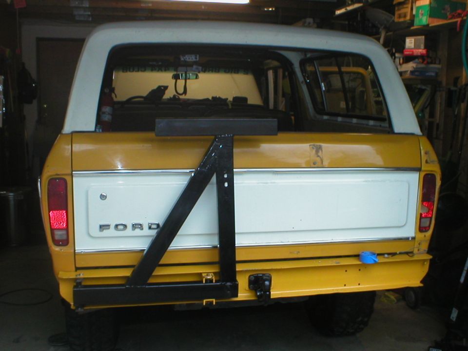 Yellow and white 1978 Ford Bronco rear view with a black swing-away spare tire carrier
