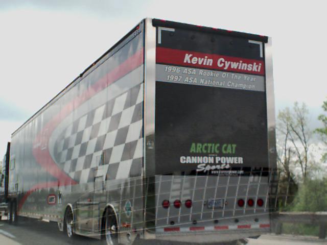 Trailer with checkerboard and red stripe graphics, "Kevin Cywinski" text, and "Arctic Cat" logo