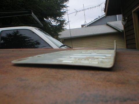 1978 Ford Bronco - Low angle view of the rear of a white vehicle, showing tinted windows and a rusty surface in the foreground.