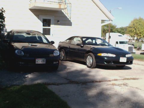 1994 Eagle Talon - Two cars are parked in a driveway next to a house, with a semi-truck visible in the distance.