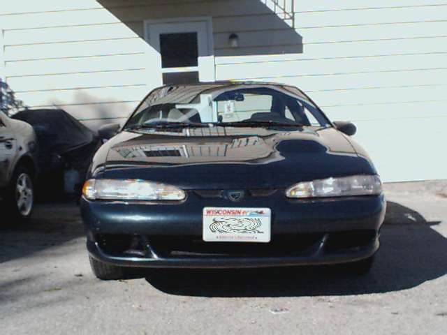 Dark blue sedan front view, parked in front of a building. License plate visible